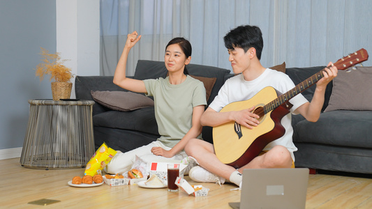 年轻情侣居家吃零食看电视视频