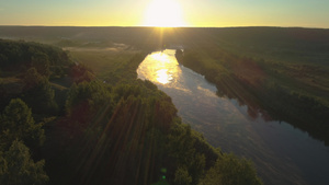 无人驾驶飞机在阳光照耀的日出时飞越森林和河流上空20秒视频