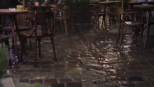 晚上大雨中的老街咖啡馆湿木家具桌椅雨滴落在潮湿的鹅卵石视频