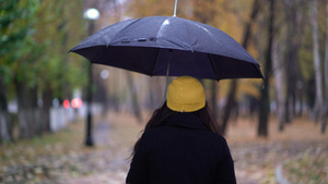 一位戴着防护面具的年轻女子在雨伞下在公园里散步18秒视频