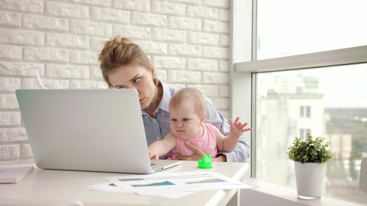 工作母亲与婴儿在桌边工作母亲与美丽的婴儿在手边视频