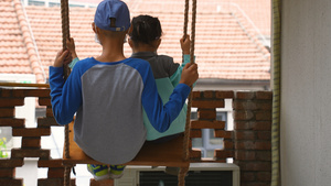 城市屋顶阳台上居家生活娱乐荡秋千的儿童背影4k亲子素材25秒视频