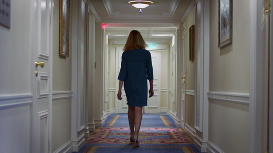 身着蓝裙子的年轻女在舒适酒店走廊上行视频