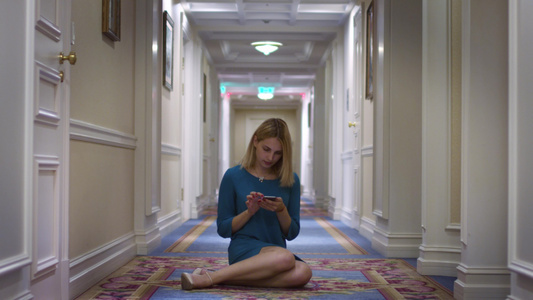 坐在长走廊中层使用移动电话的年轻妇女视频