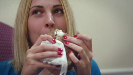 面对年轻女人咬着美味的三明治看着镜头视频