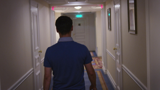 穿着蓝衬衫的年轻人沿走廊在旅馆后视线的走廊上视频