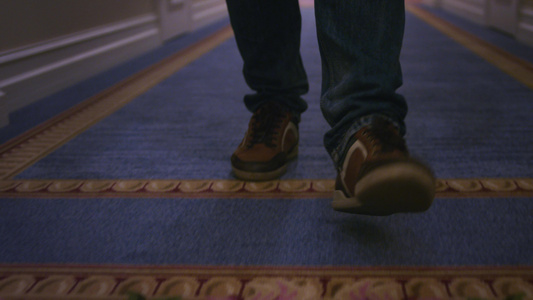 穿着棕色运动鞋的男子在长Corrido蓝地毯上行走视频