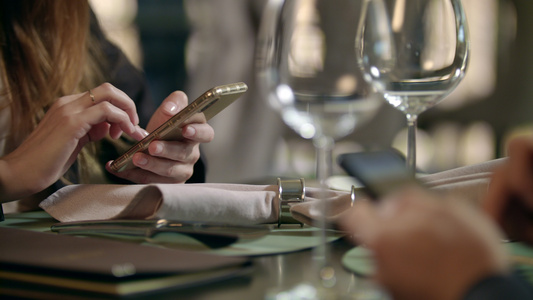男女用手在咖啡馆的智能手机上发短信视频