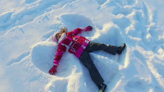 小孩做雪天使美丽的女孩在雪中玩耍视频