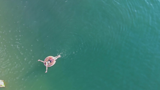 一个女孩在充气环上浮在湖边的海边有个男人在那里等着视频