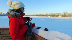 年轻妇女在冬季公园喝茶或咖啡20秒视频