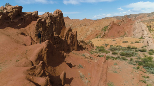 旅游人在晴天拍摄红色峡谷和蓝天鸟瞰图无人机环绕四周视频