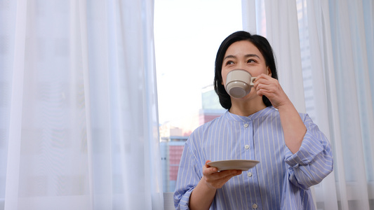 短发中年女性窗前喝咖啡视频