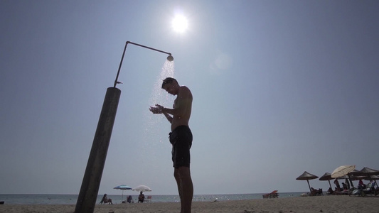 男人在沙滩上洗澡与太阳对抗电影拍摄镜头视频