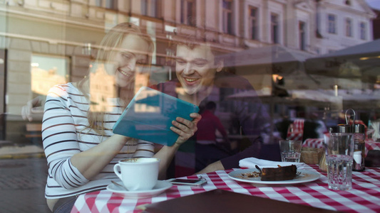 快乐的年轻夫妇在咖啡馆里有平板电脑视频