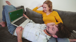一对情侣在沙发上看着笔记本电脑男孩躺在女孩腿上绿屏6秒视频