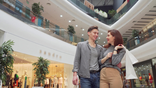低角度拍摄一对年轻夫妇在购物中心周围看的低角度镜头视频
