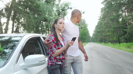 年轻夫妇在乘车旅行时使用智能电话视频