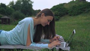 一位年轻女子躺在草坪上在电脑上得到一个信息11秒视频