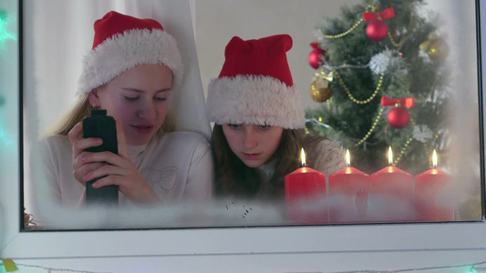 窗口家里圣诞树玩智能手机的小女孩视频