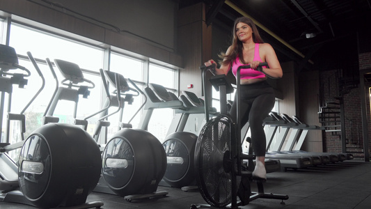 美丽的快乐加体型的女人在机车上锻炼在健身房骑自行车视频