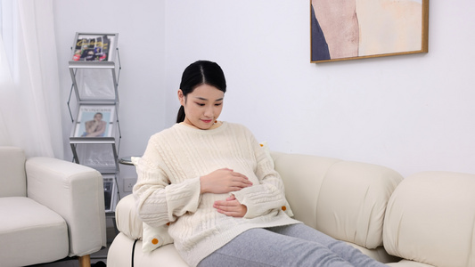 居家孕妇坐在沙发上抚摸肚子视频