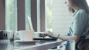 用笔记本电脑做背景工作的女性在桌子上喝咖啡15秒视频