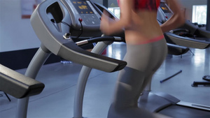女子在健身中心运动机上听音乐跑步14秒视频