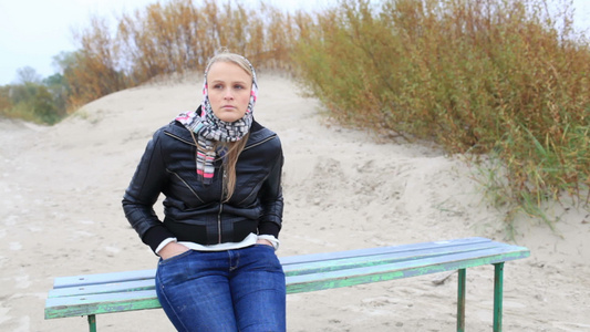年轻女孩坐在海边的长凳上视频