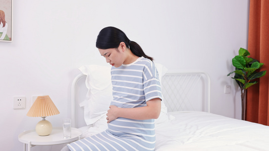 年轻孕妇坐在床上抚摸肚子视频