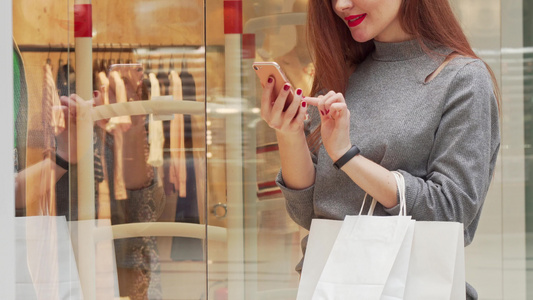女人在购物中心购物时笑着看她的智能手机视频