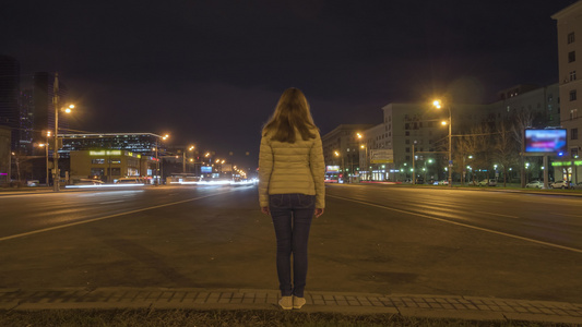 妇女静静地站立和夜间在高速公路上行驶汽车的时间已过视频