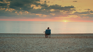 坐在折叠的旅游椅上看着海面的女孩24秒视频