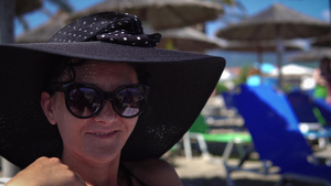 坐在沙滩度假胜地上戴着帽子微笑的美女10秒视频