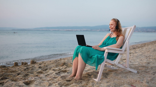 女人在沙滩上放松她用笔记本电脑说话视频