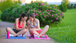 在户外锻炼和看智能手机两个运动女孩12秒视频