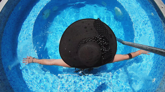 快乐的黑帽子女人在游泳池温泉里放松视频