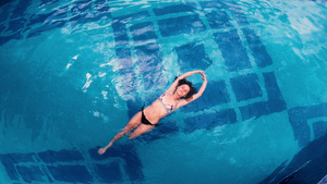 漂浮在游泳池水面上的年轻女子的空中最高视线12秒视频