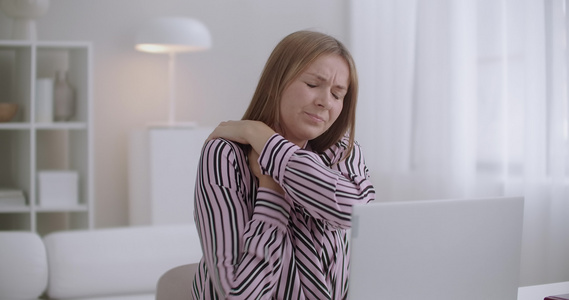 使用笔记本电脑的年轻妇女感到脖子疼痛慢性子宫颈骨质视频