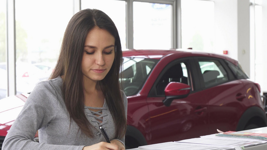 具有吸引力的年轻年轻女性驾驶员在汽车经销商填写文件视频