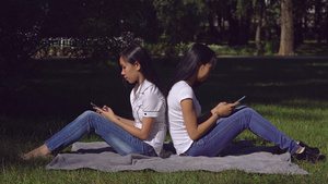 两个女生在户外背对背玩手机14秒视频