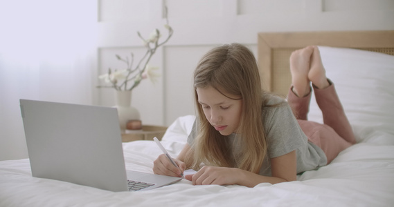 女学生在家用笔记本电脑在线聊天躺在床上兴高采烈地说话视频