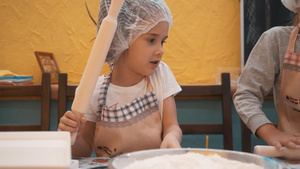 在学校厨房准备面团的一次性帽子的小女孩女厨师在烹饪12秒视频