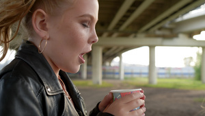 冰冻的朋克女孩手里拿着热饮在城市街道上取暖穿着黑色17秒视频