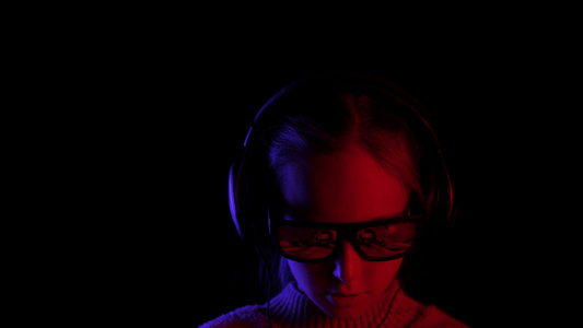 女孩用太阳镜和耳机在黑暗中浏览电话视频