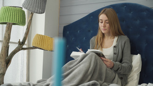 一个年轻女孩在床上看一本书12秒视频