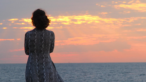 在日出和海景的背景下穿着夏装的年轻女子看着大海11秒视频