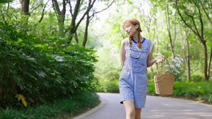 女孩携花篮走在林荫小路上22秒视频