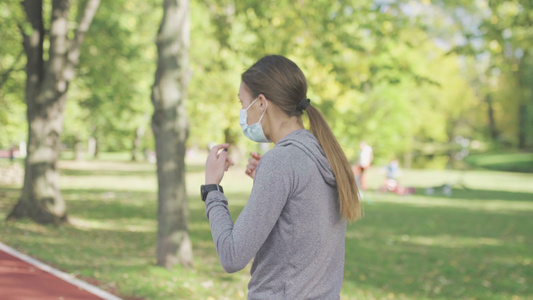跑步女孩在公园的全天候合成跑道表面上行走戴上防护面罩视频