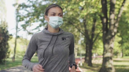身戴保护面罩在公园内所有天气合成轨道表面跑动的健身视频